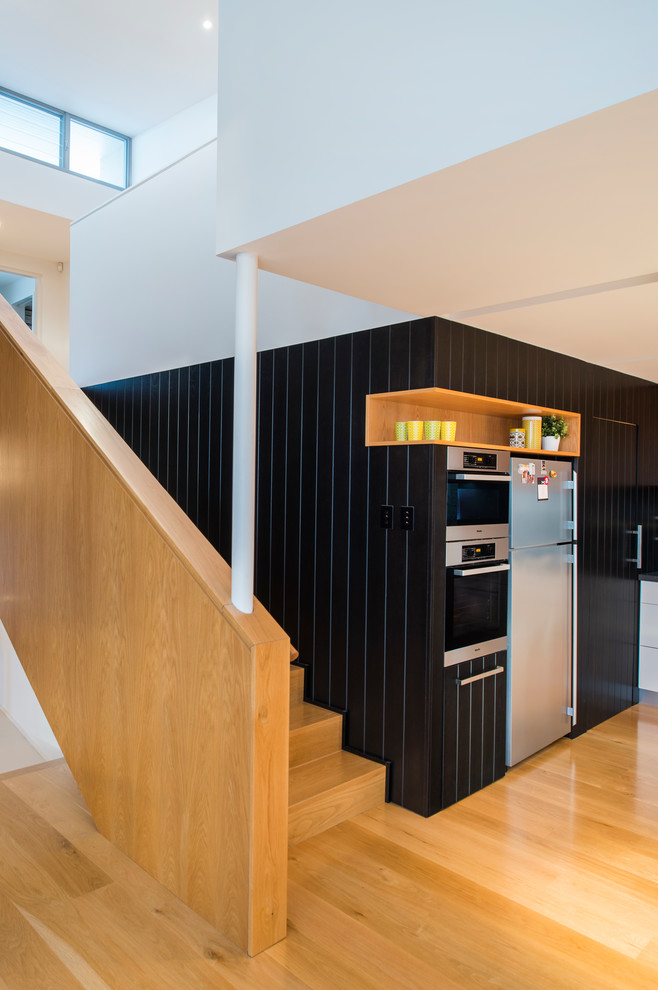 Inspiration for a mid-sized modern light wood floor eat-in kitchen remodel in Perth with a double-bowl sink, flat-panel cabinets, black cabinets, stainless steel appliances and an island