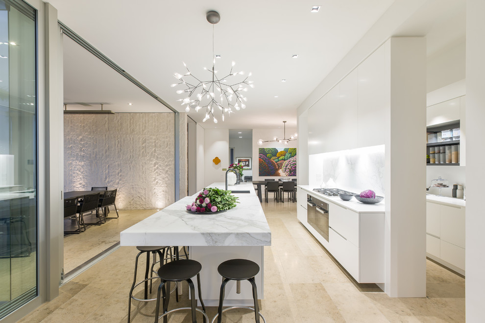 Contemporary open plan kitchen in Auckland with flat-panel cabinets, white cabinets, white splashback, stainless steel appliances, light hardwood flooring, an island and beige floors.
