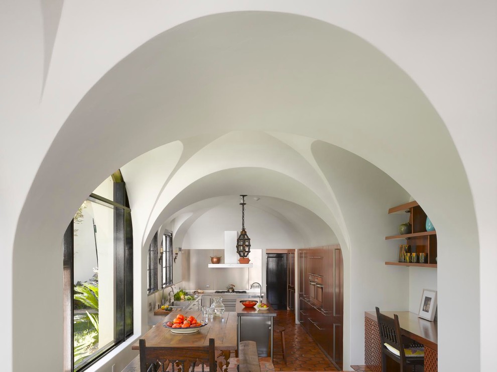 Example of a mid-sized 1950s galley terra-cotta tile enclosed kitchen design in Los Angeles with an undermount sink, flat-panel cabinets, medium tone wood cabinets, stainless steel countertops, metallic backsplash, metal backsplash, stainless steel appliances and an island