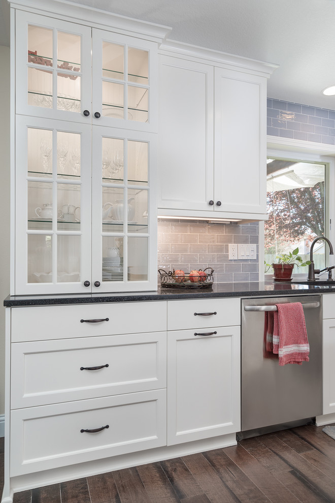Foto på ett mellanstort lantligt kök, med en integrerad diskho, släta luckor, vita skåp, träbänkskiva, grått stänkskydd, stänkskydd i tunnelbanekakel, rostfria vitvaror, mörkt trägolv och en köksö