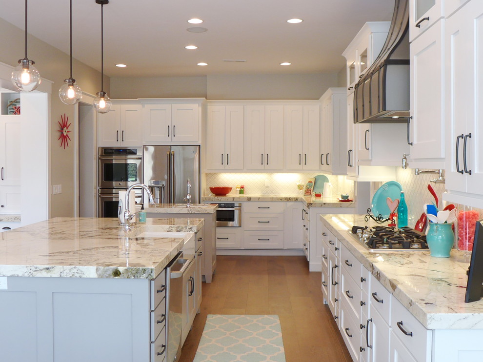 Example of a classic medium tone wood floor and brown floor open concept kitchen design in Salt Lake City with a farmhouse sink, white cabinets, granite countertops, white backsplash, stainless steel appliances, two islands, shaker cabinets and subway tile backsplash