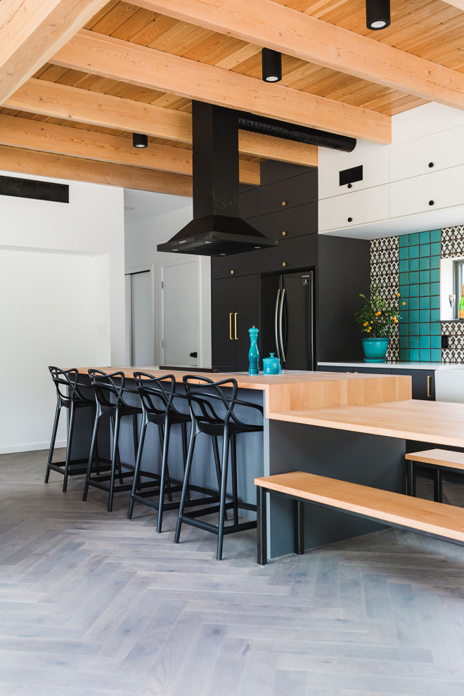 Immagine di una cucina design con ante lisce, top in legno, parquet scuro, pavimento grigio, ante nere, elettrodomestici neri, travi a vista e soffitto in legno