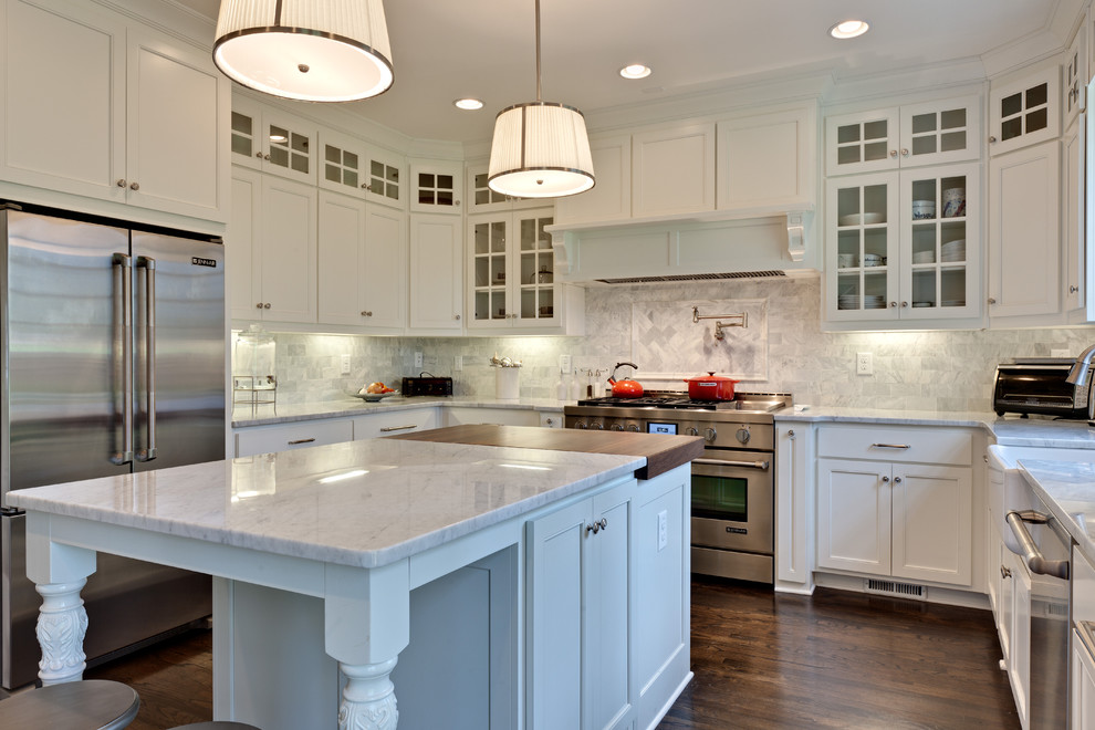 Klassisk inredning av ett mellanstort kök, med rostfria vitvaror, en rustik diskho, vita skåp, marmorbänkskiva, stänkskydd i stenkakel, mörkt trägolv, en köksö, luckor med infälld panel och grått stänkskydd