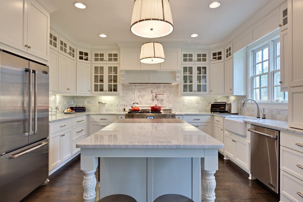 Inredning av ett klassiskt mellanstort kök, med rostfria vitvaror, en rustik diskho, stänkskydd i stenkakel, marmorbänkskiva, vita skåp, mörkt trägolv, en köksö, luckor med infälld panel och grått stänkskydd