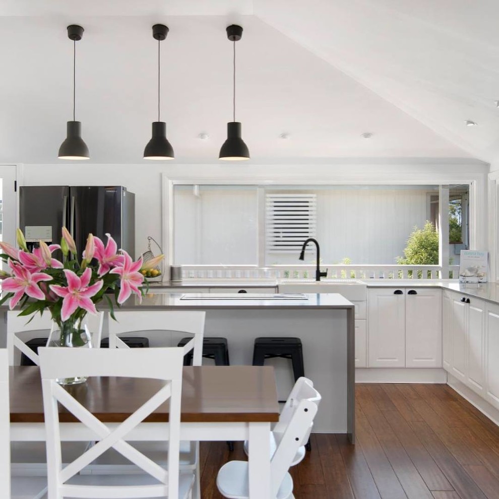 Inspiration for a large modern l-shaped bamboo floor and brown floor open concept kitchen remodel in Brisbane with a farmhouse sink, shaker cabinets, white cabinets, quartz countertops, stainless steel appliances, an island and gray countertops