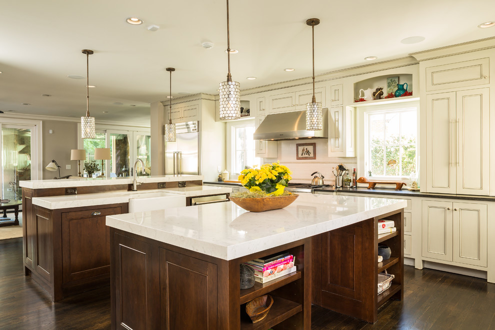 Eat-in kitchen - large traditional galley dark wood floor and brown floor eat-in kitchen idea in Atlanta with a farmhouse sink, recessed-panel cabinets, white cabinets, granite countertops, white backsplash, subway tile backsplash, stainless steel appliances and two islands