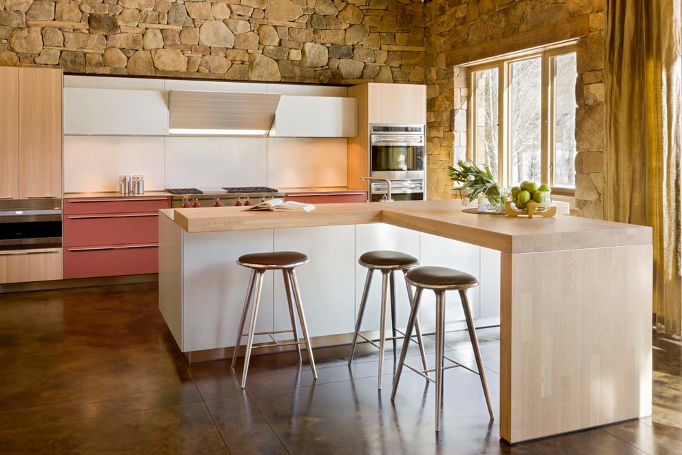 Zweizeilige Moderne Küche mit flächenbündigen Schrankfronten, hellen Holzschränken, Küchenrückwand in Weiß, Küchengeräten aus Edelstahl, Betonboden, Kücheninsel und braunem Boden in Denver
