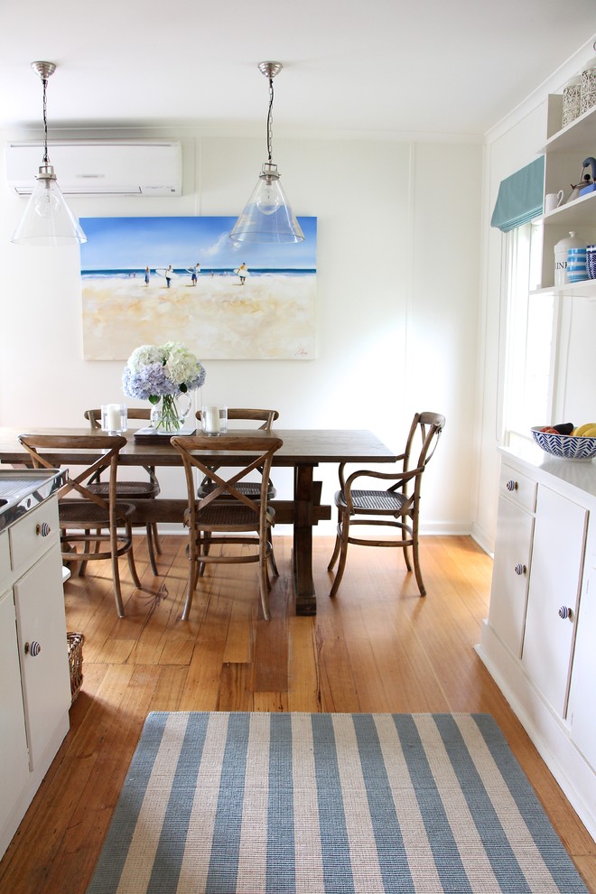 На фото: маленькая п-образная кухня в морском стиле с обеденным столом и белыми фасадами для на участке и в саду