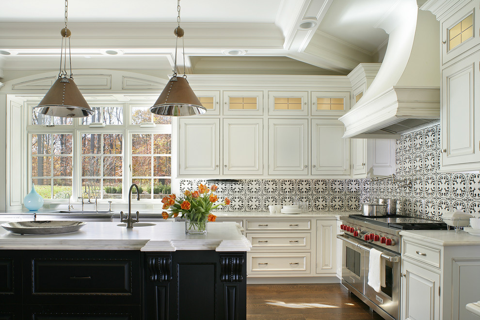 Bild på ett stort vintage kök, med luckor med upphöjd panel, vita skåp, flerfärgad stänkskydd, rostfria vitvaror, en köksö, en undermonterad diskho, mellanmörkt trägolv och stänkskydd i cementkakel