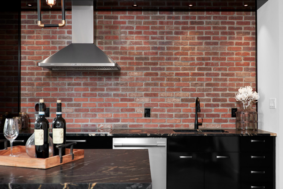 This is an example of an industrial kitchen in Toronto with a submerged sink, flat-panel cabinets, black cabinets, quartz worktops, red splashback, brick splashback, stainless steel appliances, light hardwood flooring, brown floors and black worktops.