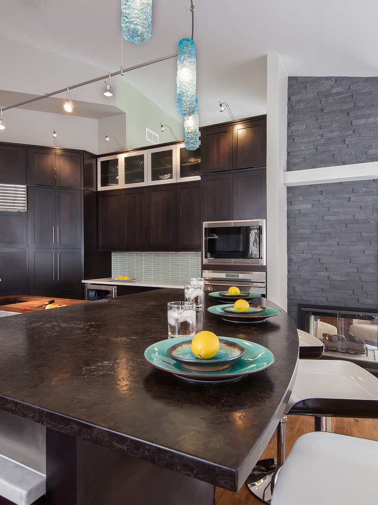 Example of a trendy kitchen design in Denver with an undermount sink, shaker cabinets, dark wood cabinets, granite countertops, blue backsplash, glass tile backsplash and stainless steel appliances