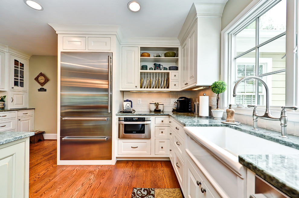 Exempel på ett klassiskt kök, med en rustik diskho, luckor med upphöjd panel, vita skåp, granitbänkskiva, vitt stänkskydd och rostfria vitvaror
