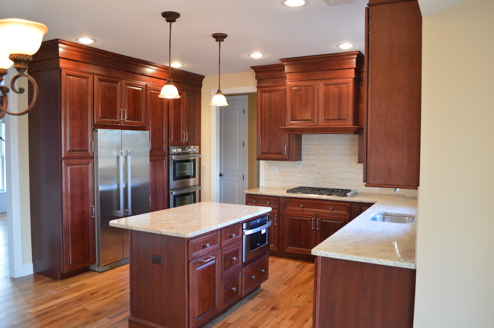 Foto på ett mellanstort vintage kök, med en undermonterad diskho, luckor med upphöjd panel, skåp i mörkt trä, granitbänkskiva, stänkskydd i keramik, rostfria vitvaror, mellanmörkt trägolv, en köksö, beige stänkskydd och brunt golv