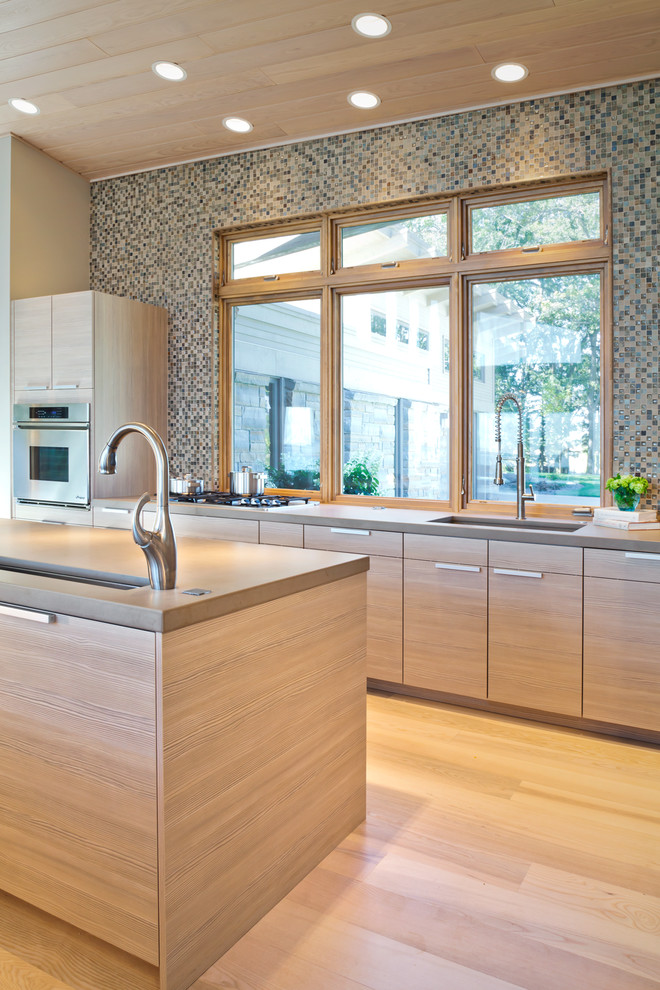 Example of a trendy light wood floor kitchen design in Minneapolis with multicolored backsplash, mosaic tile backsplash, an undermount sink, flat-panel cabinets and light wood cabinets