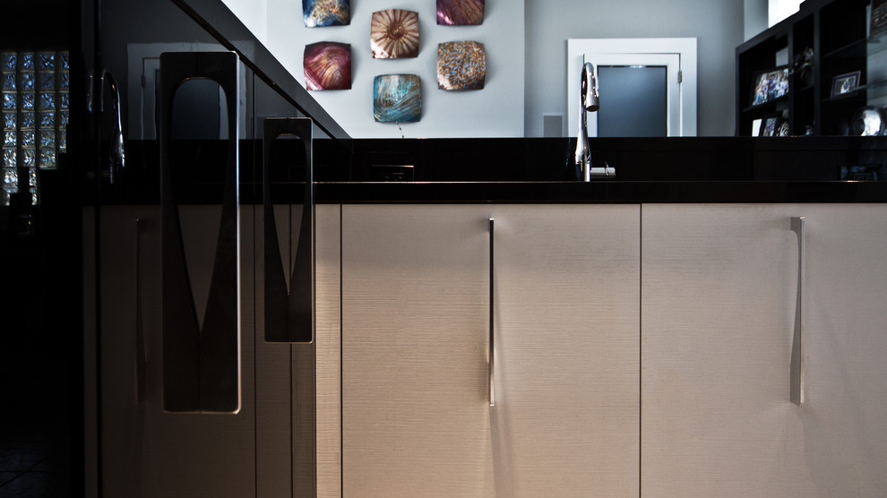 Diseño de cocina minimalista con armarios con paneles lisos, salpicadero negro, salpicadero de azulejos de vidrio y electrodomésticos de acero inoxidable