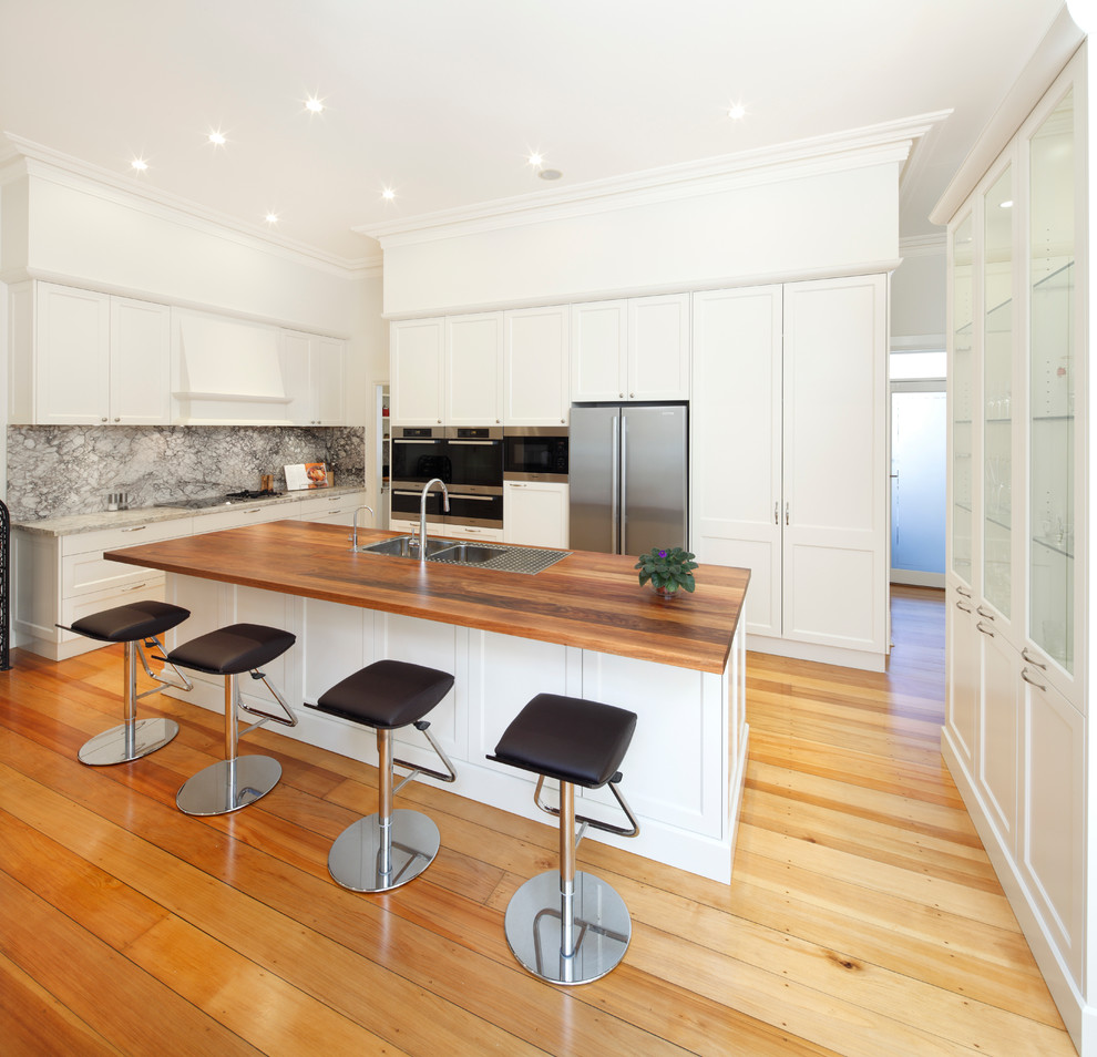 Medium sized contemporary galley kitchen/diner in Sydney with a double-bowl sink, shaker cabinets, white cabinets, stainless steel appliances, wood worktops, multi-coloured splashback, marble splashback, medium hardwood flooring and an island.