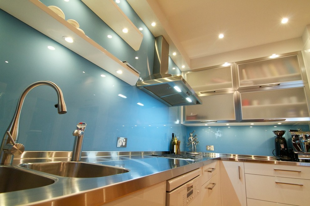 Medium sized modern l-shaped enclosed kitchen in Sydney with an integrated sink, flat-panel cabinets, white cabinets, stainless steel worktops, blue splashback, glass sheet splashback, stainless steel appliances, light hardwood flooring, an island and white worktops.
