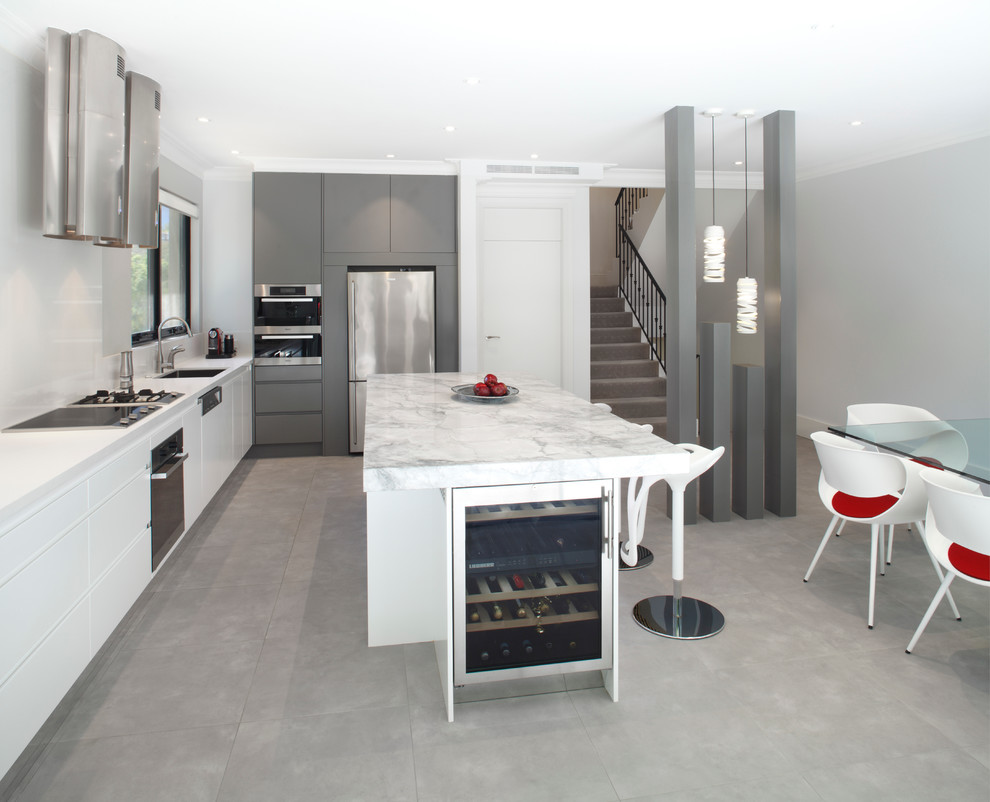 Foto på ett mellanstort funkis linjärt kök och matrum, med en undermonterad diskho, släta luckor, vita skåp, granitbänkskiva, vitt stänkskydd, glaspanel som stänkskydd, rostfria vitvaror och en köksö