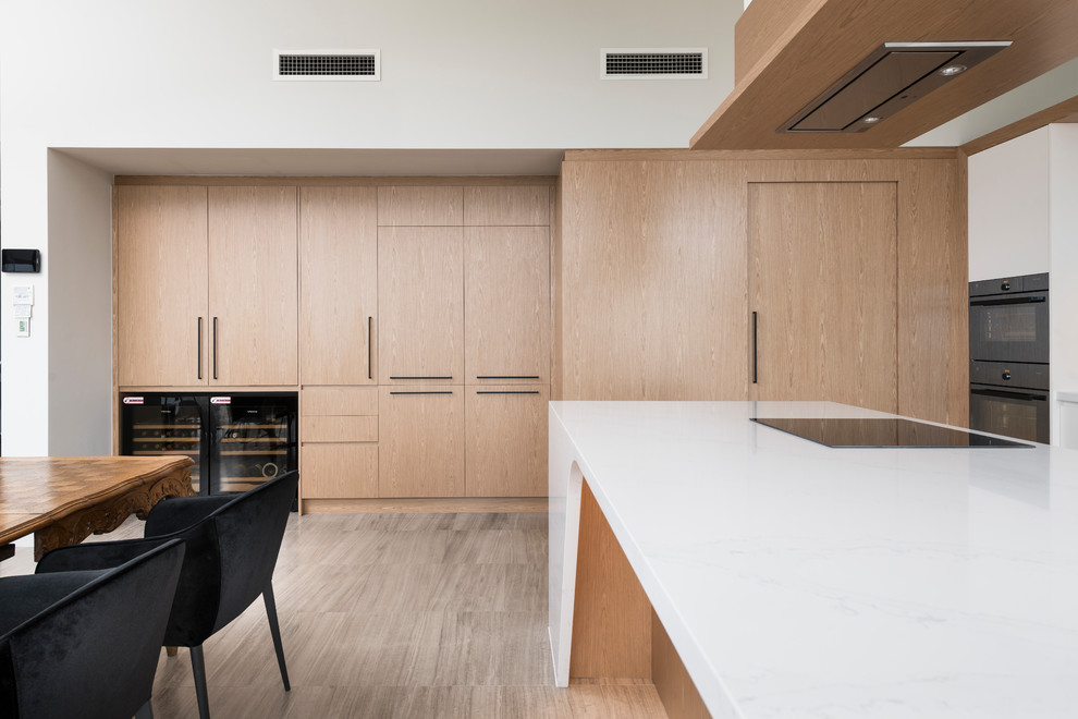 Large minimalist l-shaped porcelain tile and gray floor eat-in kitchen photo in Perth with an undermount sink, recessed-panel cabinets, light wood cabinets, solid surface countertops, white backsplash, stone slab backsplash, black appliances, an island and white countertops