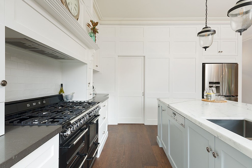 This is an example of a large classic galley kitchen/diner in Sydney with a built-in sink, shaker cabinets, white cabinets, marble worktops, white splashback, ceramic splashback, stainless steel appliances, medium hardwood flooring, no island and brown floors.