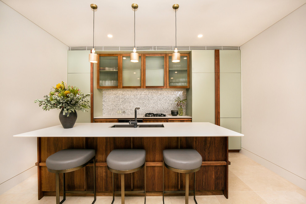 Idee per un cucina con isola centrale minimal di medie dimensioni con lavello a doppia vasca, ante di vetro, pavimento beige e top bianco