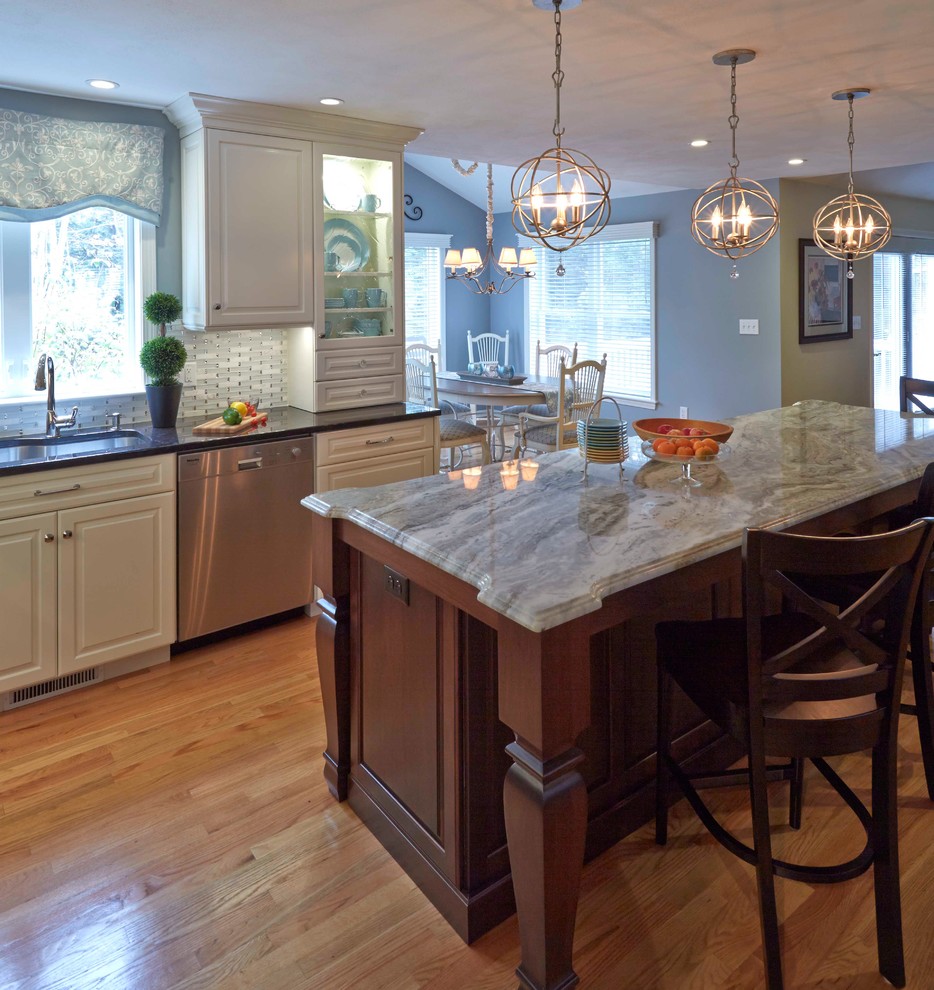 Large elegant u-shaped eat-in kitchen photo in Boston with a single-bowl sink, raised-panel cabinets, white cabinets, granite countertops, white backsplash, glass tile backsplash, stainless steel appliances and an island