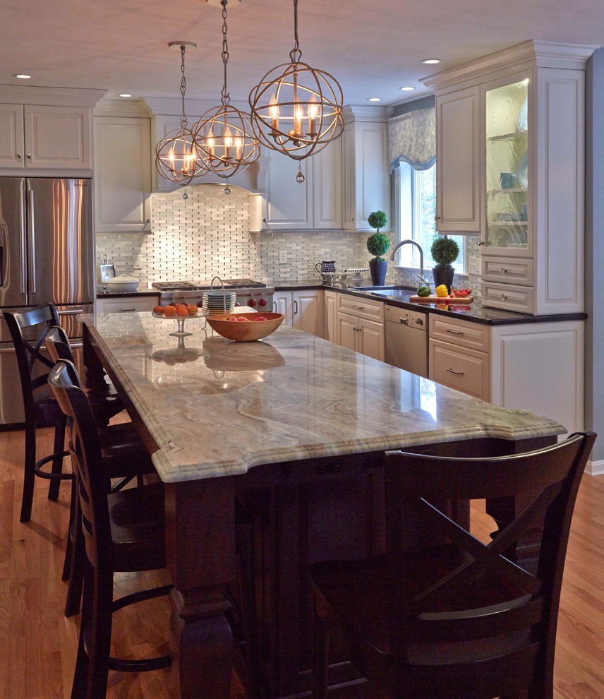 Example of a large classic u-shaped eat-in kitchen design in Boston with a single-bowl sink, raised-panel cabinets, white cabinets, granite countertops, white backsplash, glass tile backsplash, stainless steel appliances and an island