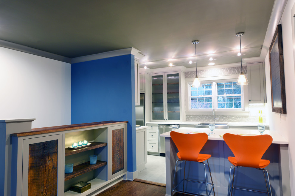 Small contemporary galley kitchen/diner in New York with a belfast sink, shaker cabinets, stainless steel appliances, dark hardwood flooring, grey cabinets, quartz worktops, grey splashback, porcelain splashback and a breakfast bar.