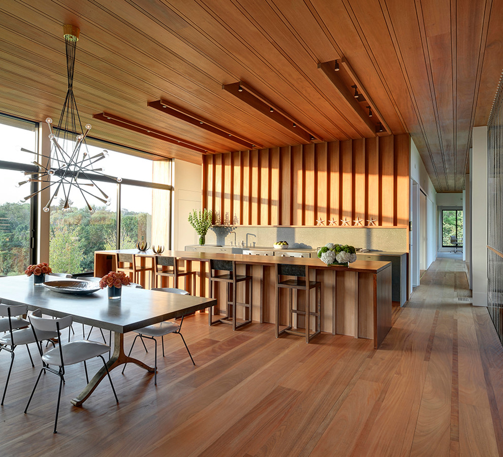 Esempio di una cucina minimalista con ante lisce, top in legno, paraspruzzi grigio, elettrodomestici da incasso e pavimento in legno massello medio