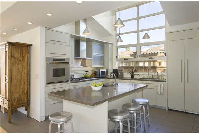 Photo of a medium sized modern l-shaped open plan kitchen in San Diego with flat-panel cabinets, composite countertops, white splashback, stone slab splashback, stainless steel appliances, porcelain flooring, an island, a single-bowl sink and white cabinets.