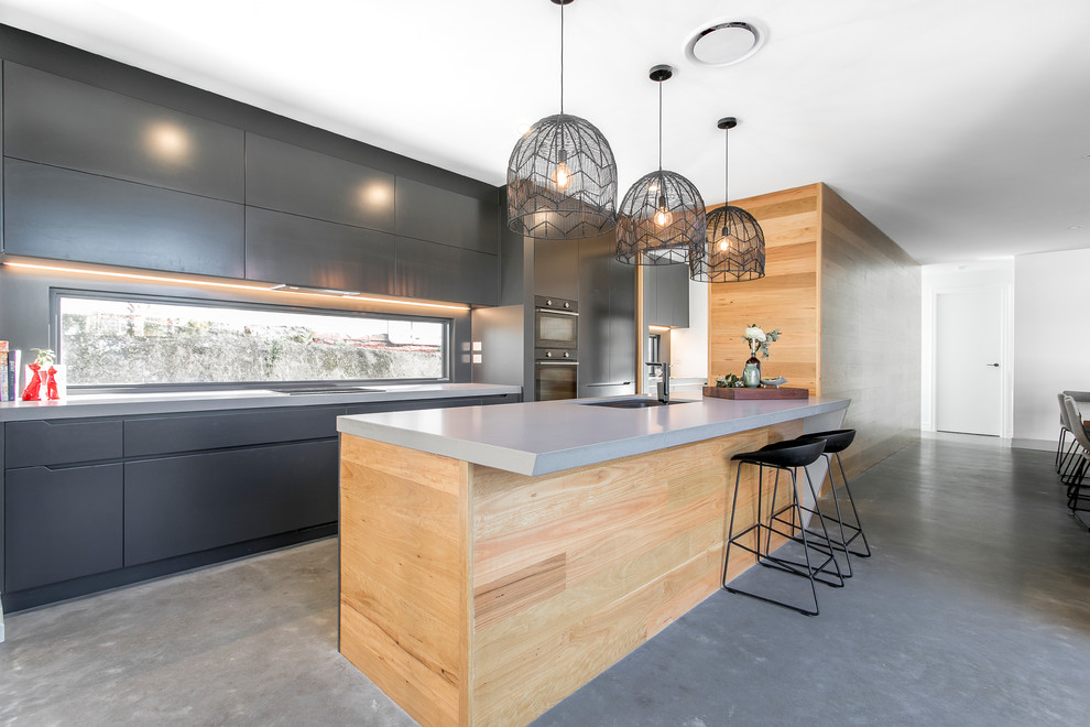 Zweizeilige, Mittelgroße Moderne Wohnküche mit Einbauwaschbecken, flächenbündigen Schrankfronten, schwarzen Schränken, Rückwand aus Spiegelfliesen, schwarzen Elektrogeräten, Betonboden, zwei Kücheninseln und grauem Boden in Brisbane