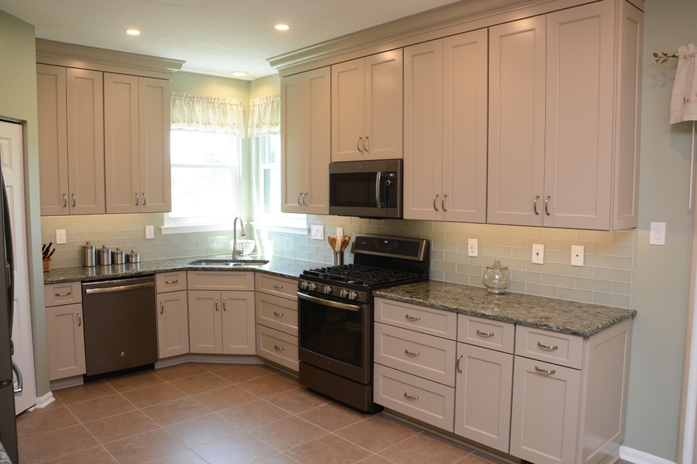 This is an example of a medium sized traditional u-shaped enclosed kitchen in DC Metro with a double-bowl sink, recessed-panel cabinets, grey cabinets, engineered stone countertops, green splashback, glass tiled splashback, stainless steel appliances, no island, beige floors and grey worktops.