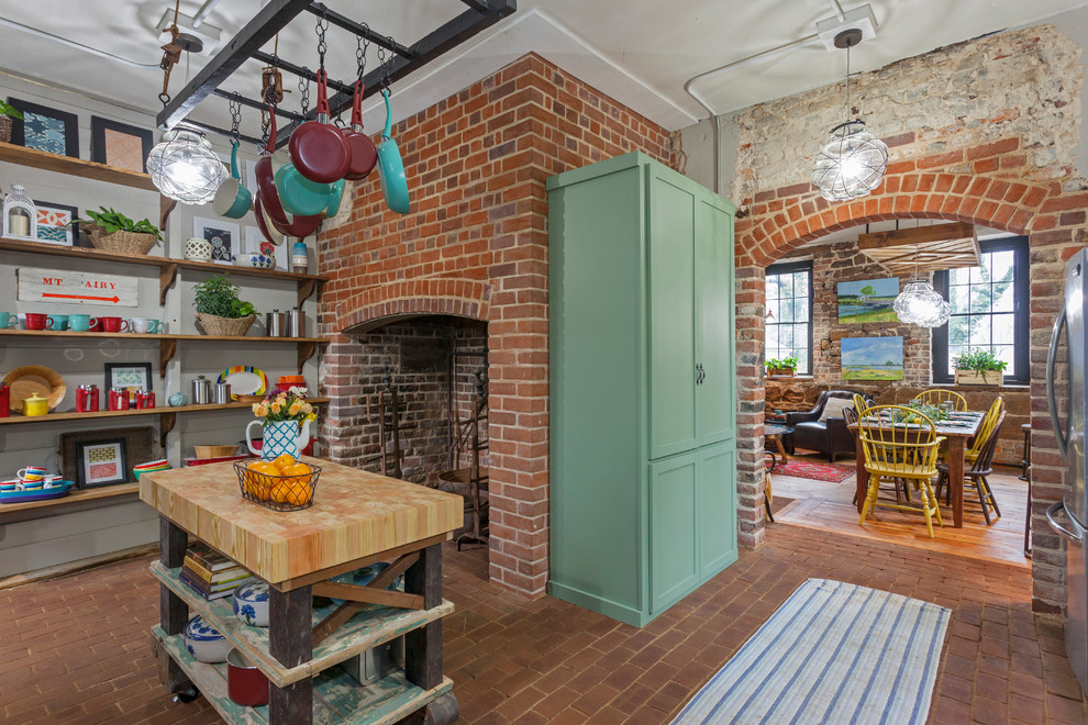 Exemple d'une cuisine linéaire éclectique fermée et de taille moyenne avec un évier de ferme, un placard à porte shaker, des portes de placards vertess, un plan de travail en bois, une crédence beige, un sol en brique et un sol rouge.