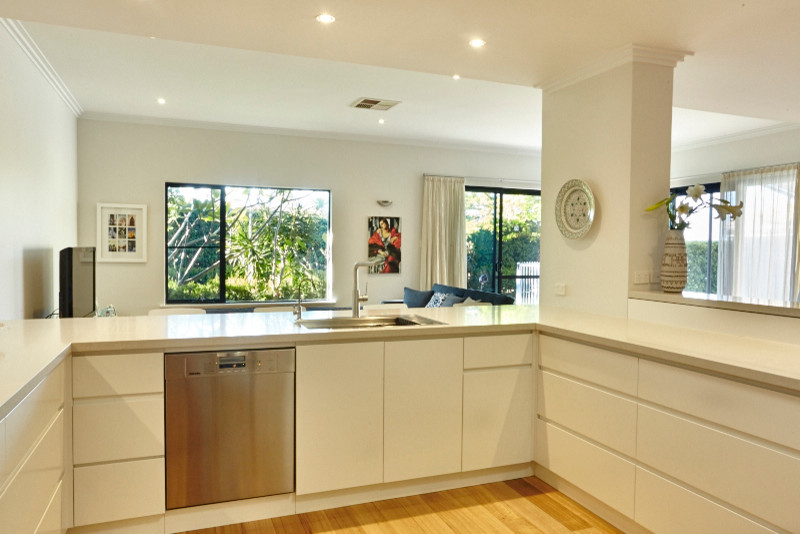 Inspiration for a medium sized contemporary u-shaped kitchen/diner in Perth with a built-in sink, beaded cabinets, white cabinets, engineered stone countertops, grey splashback, mosaic tiled splashback, stainless steel appliances, medium hardwood flooring and no island.