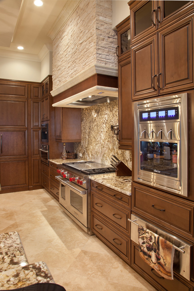 Inspiration for a mediterranean l-shaped travertine floor open concept kitchen remodel in Orlando with a farmhouse sink, raised-panel cabinets, medium tone wood cabinets, granite countertops, stone slab backsplash, stainless steel appliances, two islands and multicolored backsplash