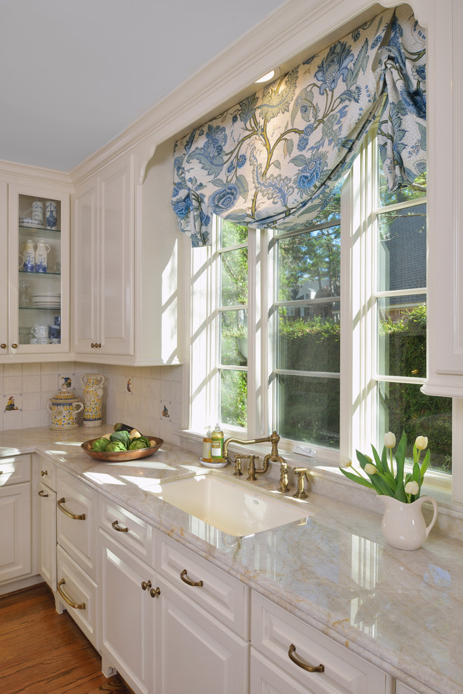 Bild på ett stort vintage kök, med en undermonterad diskho, luckor med upphöjd panel, vita skåp, granitbänkskiva, vitt stänkskydd, stänkskydd i keramik, rostfria vitvaror, mellanmörkt trägolv och en köksö