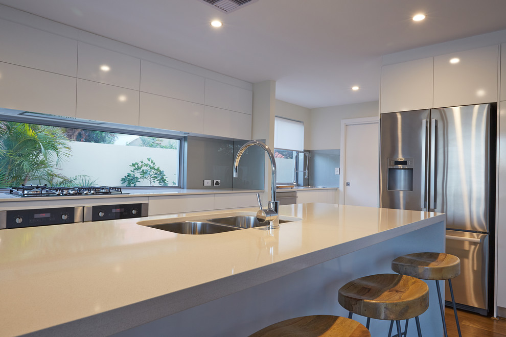 Trendy medium tone wood floor kitchen photo in Perth with an undermount sink, flat-panel cabinets, white cabinets, quartz countertops, metallic backsplash, stainless steel appliances and an island