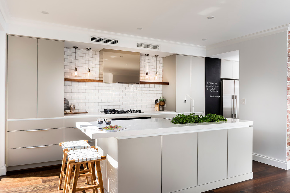 This is an example of a scandinavian single-wall kitchen in Perth with a built-in sink, flat-panel cabinets, grey cabinets, white splashback, metro tiled splashback, stainless steel appliances, dark hardwood flooring and an island.