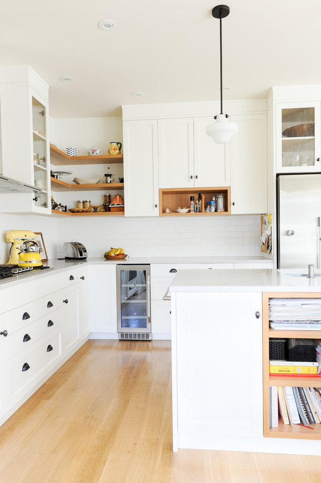 Idéer för ett mellanstort minimalistiskt vit kök, med en undermonterad diskho, skåp i shakerstil, vita skåp, bänkskiva i koppar, vitt stänkskydd, stänkskydd i tunnelbanekakel, rostfria vitvaror, ljust trägolv, en köksö och brunt golv