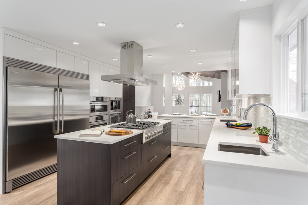 Moderne Wohnküche mit Unterbauwaschbecken, flächenbündigen Schrankfronten, weißen Schränken, Granit-Arbeitsplatte, Küchenrückwand in Weiß, Rückwand aus Mosaikfliesen, Küchengeräten aus Edelstahl, Vinylboden und Kücheninsel in Vancouver