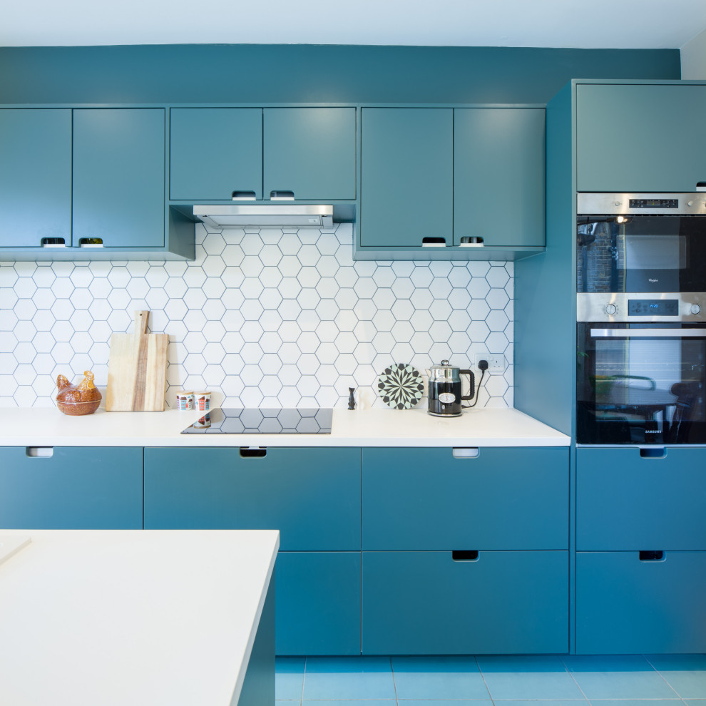 Пример оригинального дизайна: прямая кухня-гостиная в современном стиле с плоскими фасадами, синими фасадами, мраморной столешницей, белым фартуком, фартуком из керамической плитки, техникой из нержавеющей стали, полом из цементной плитки, островом, синим полом и белой столешницей