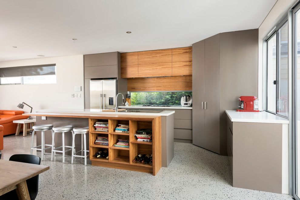 Inredning av ett modernt mellanstort kök, med en undermonterad diskho, bänkskiva i kvarts, glaspanel som stänkskydd, rostfria vitvaror, betonggolv och en köksö