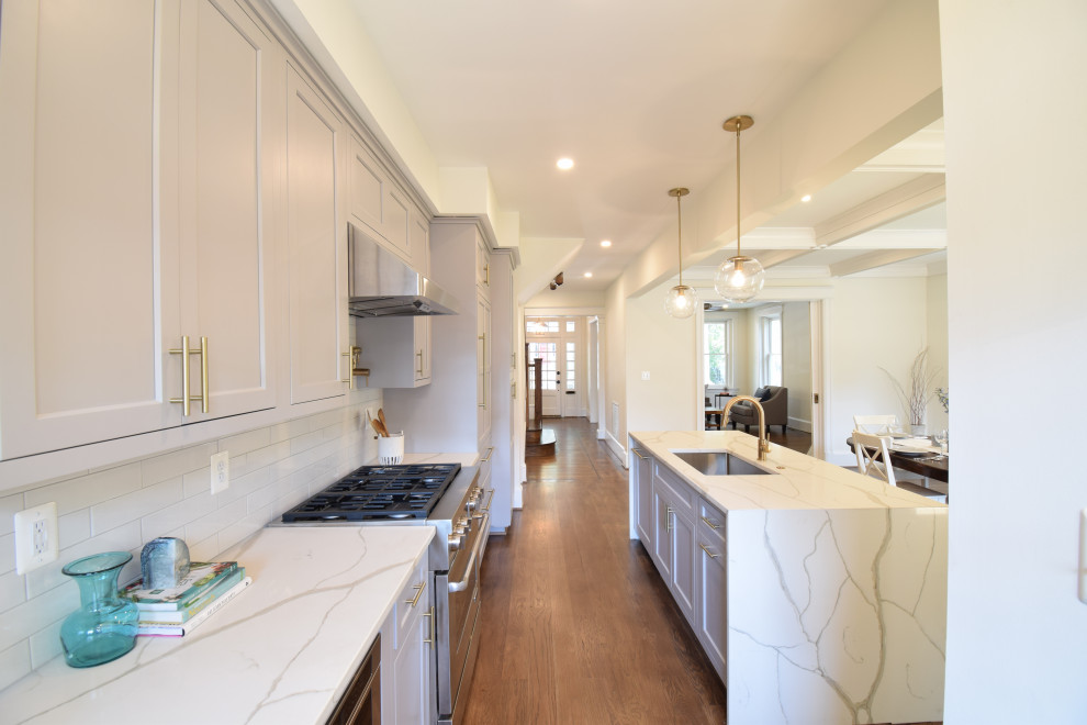 Eat-in kitchen - large transitional single-wall dark wood floor and brown floor eat-in kitchen idea in DC Metro with an undermount sink, recessed-panel cabinets, gray cabinets, quartz countertops, white backsplash, glass tile backsplash, paneled appliances, an island and multicolored countertops