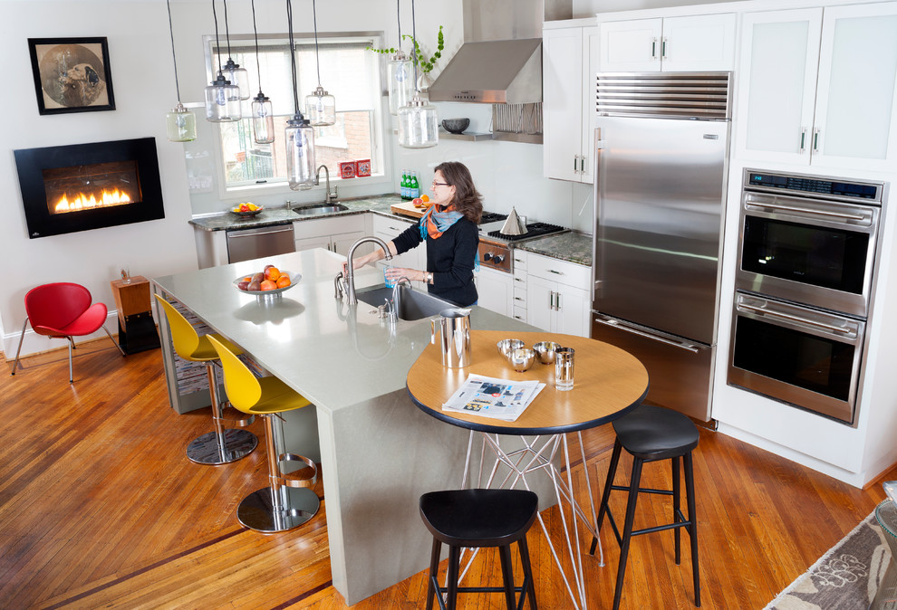 Photo of a large modern l-shaped open plan kitchen in Other with a submerged sink, shaker cabinets, white cabinets, stainless steel appliances, medium hardwood flooring, an island and brown floors.