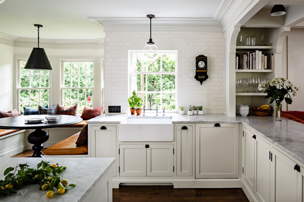 Klassische Wohnküche mit Landhausspüle, Schrankfronten im Shaker-Stil, weißen Schränken, Küchenrückwand in Weiß, Rückwand aus Metrofliesen und dunklem Holzboden in Portland