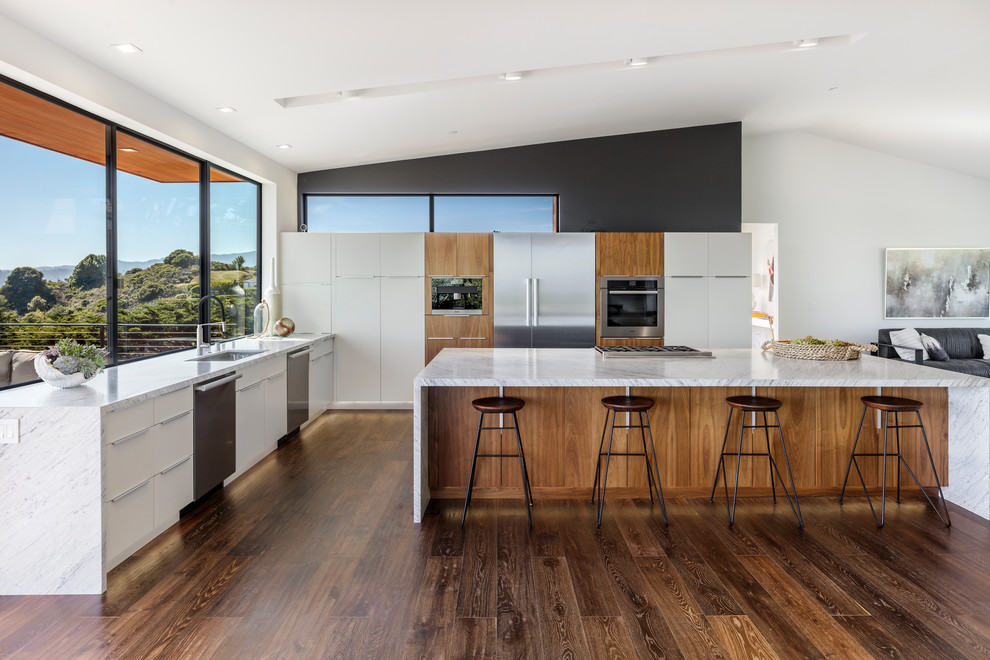 Inspiration for a large contemporary l-shaped brown floor and dark wood floor open concept kitchen remodel in San Francisco with an undermount sink, flat-panel cabinets, white cabinets, marble countertops, stainless steel appliances, an island and gray countertops