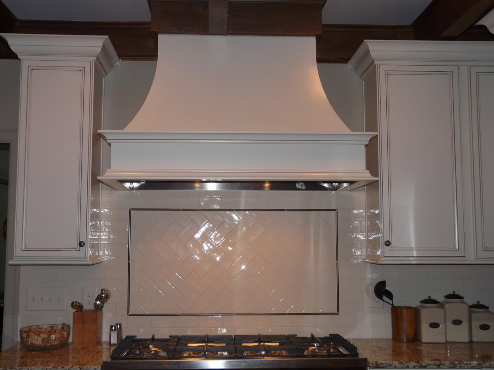 Klassisk inredning av ett kök och matrum, med en rustik diskho, släta luckor, granitbänkskiva, stänkskydd i porslinskakel och rostfria vitvaror