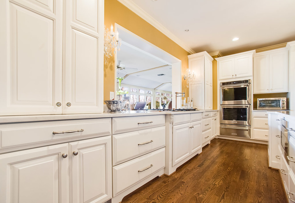 Large elegant l-shaped eat-in kitchen photo in Birmingham with raised-panel cabinets, white cabinets, quartz countertops, stainless steel appliances and an island