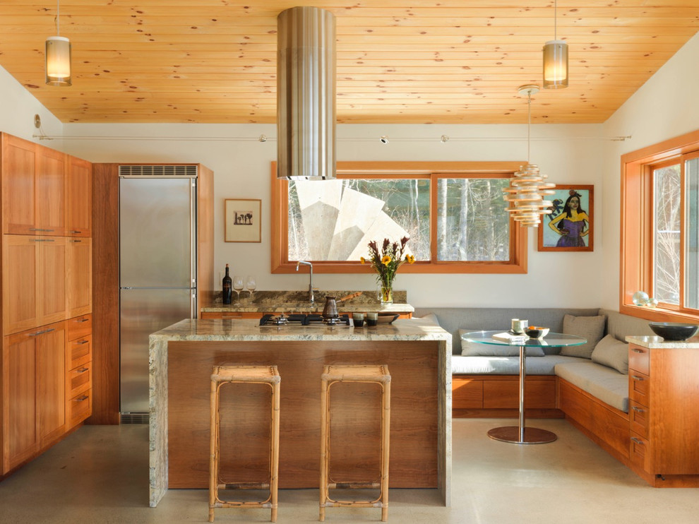 Cette photo montre une petite cuisine américaine montagne en L et bois brun avec un placard à porte shaker, un électroménager en acier inoxydable, îlot, un évier encastré, un plan de travail en granite, un sol beige et sol en béton ciré.