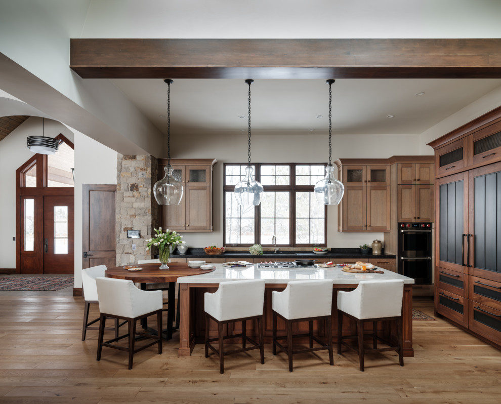 Large mountain style medium tone wood floor kitchen photo in Denver with a double-bowl sink, flat-panel cabinets, light wood cabinets, wood countertops, paneled appliances, an island and black countertops